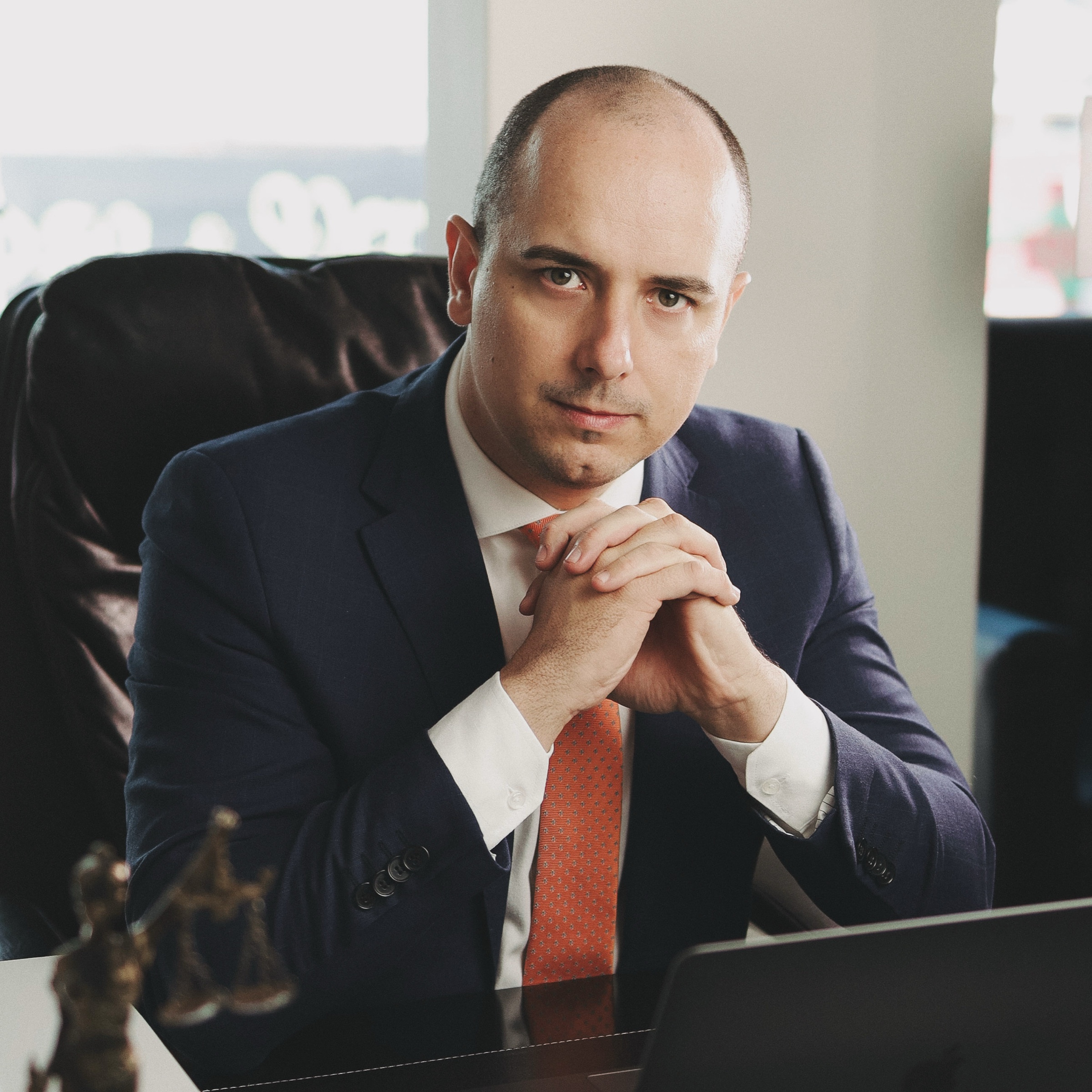 Edson Pratti à mesa, ao lado de uma estátua da Justiça